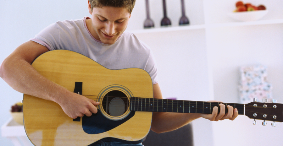 A Teenage Boy Playing his acoustic guitar.