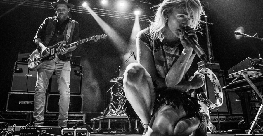 A Grayscale Image Of A Musical Concert That Showing A Female Vocalist Performing While Lead Guitarist On His Track - Musical Photography Concept.